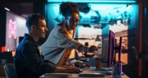 Two colleagues collaborating at a computer in a colorful neon-lit workspace