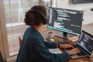 Developer writing test code on multiple monitors in office