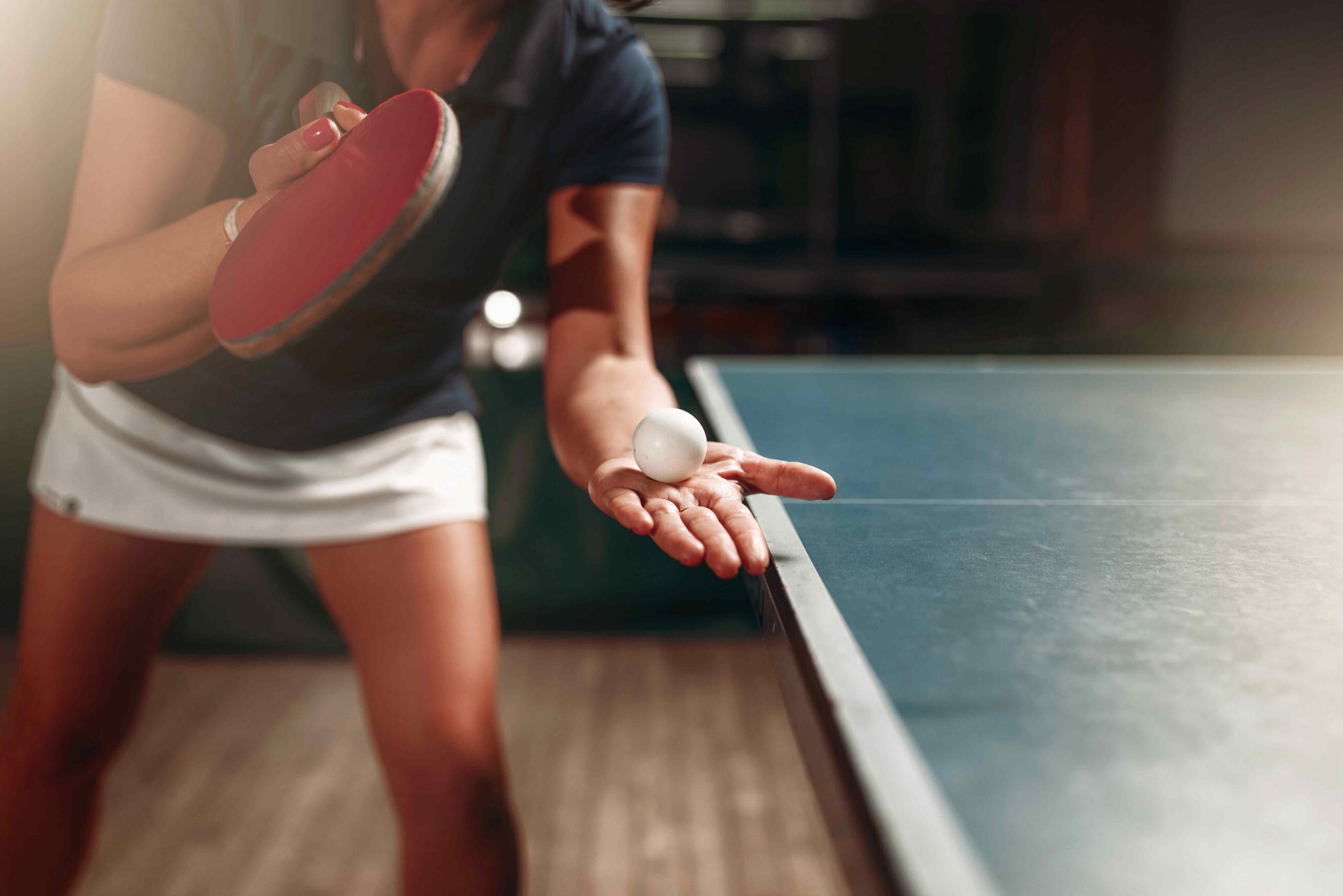 Adult woman plays table tennis preparing to serve scaled
