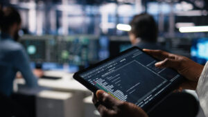 QA engineer reviewing automated regression testing results on a tablet in a tech operations center