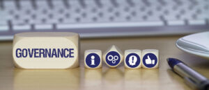 Wooden blocks spelling governance with information and process icons on a desk