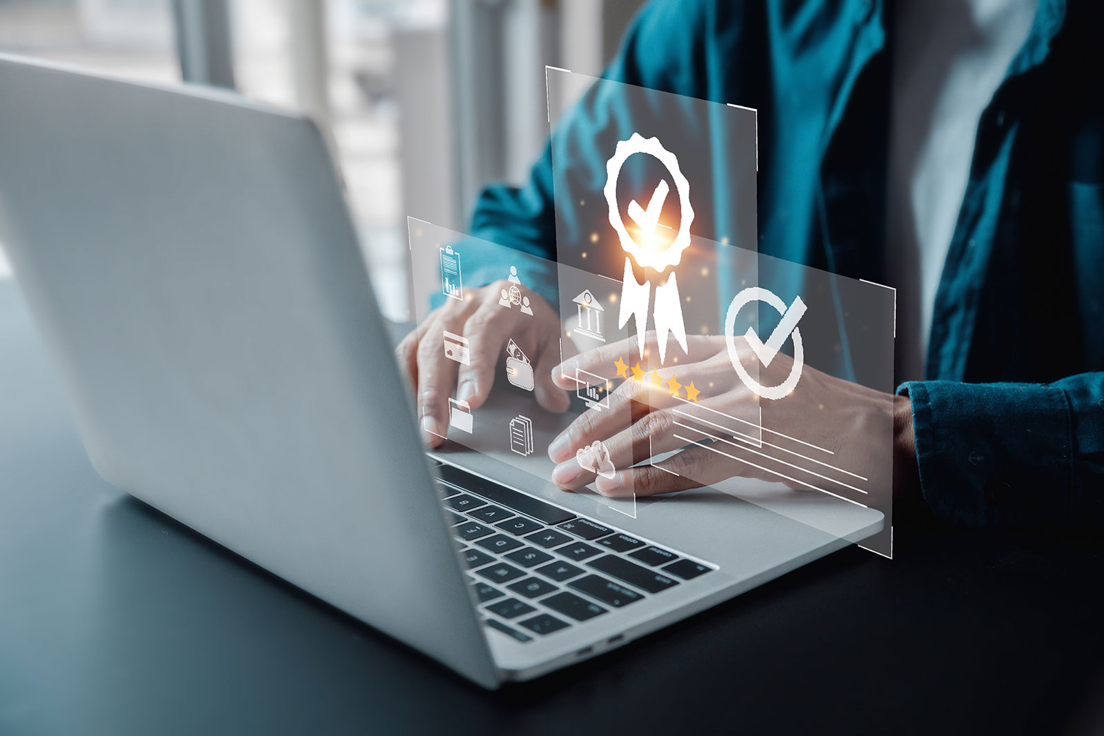 Hands on a laptop with glowing quality assurance and achievement icons overlay
