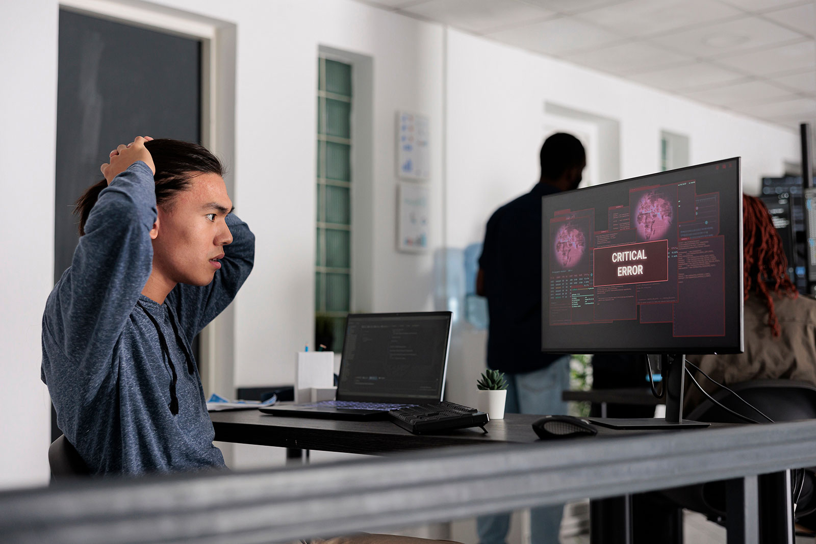 Stressed developer reacting to critical error on screen during ERP system testing