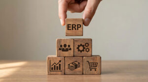 Hand placing ERP wooden block on top of stacked blocks with business icons