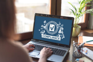 Person working on a laptop displaying a compliance concept graphic