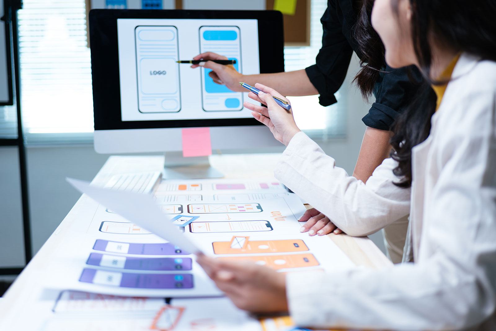 Designers reviewing mobile UI wireframes for UX usability and accessibility testing