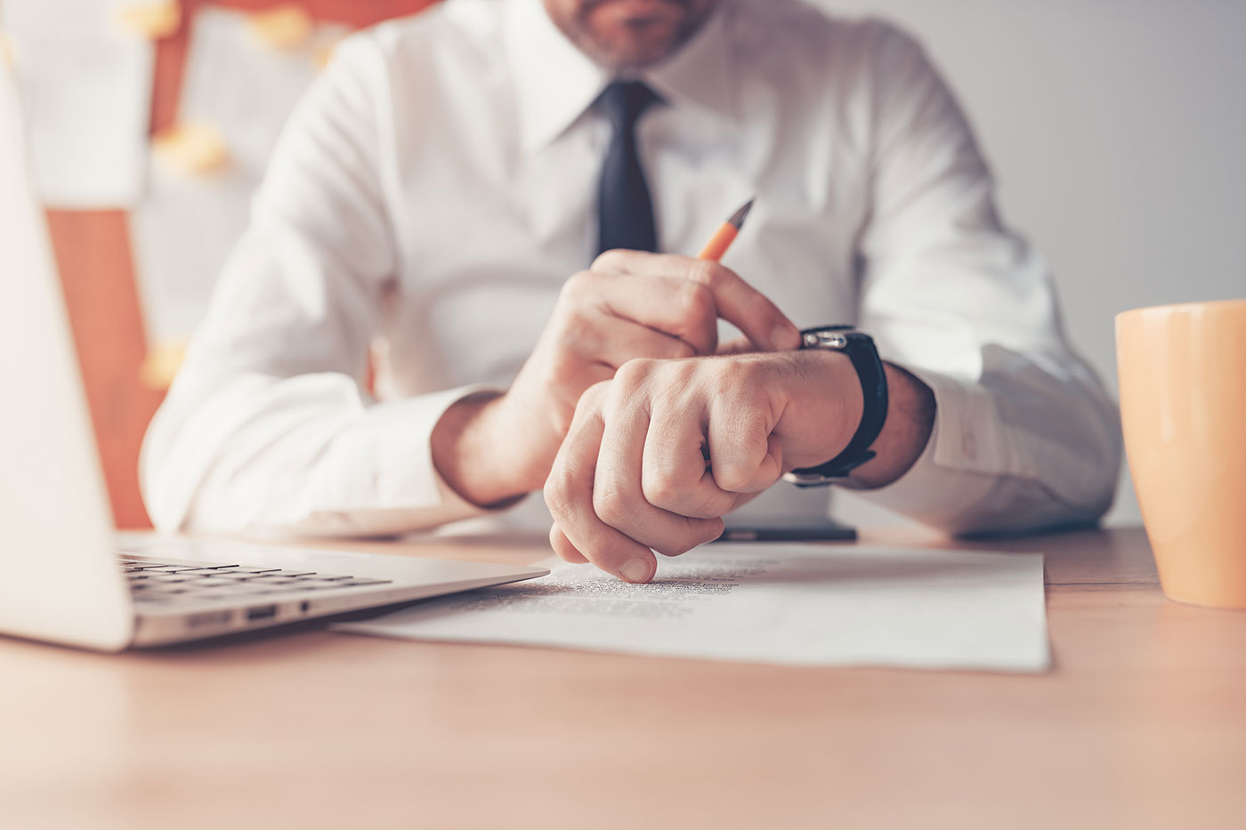 Businessman checking his watch while working with documents on a desk