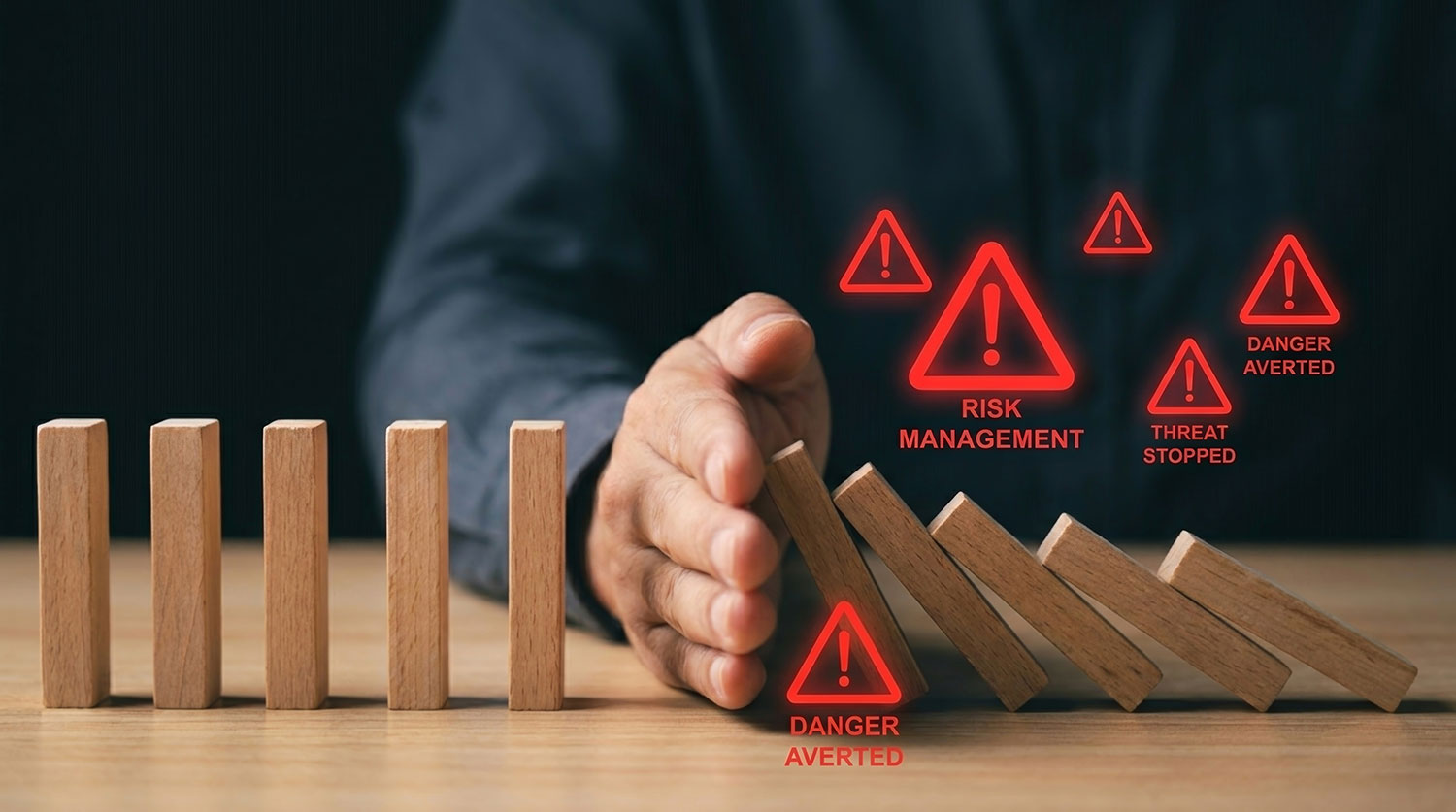 Hand stopping falling dominoes with risk warning icons representing security vulnerability testing