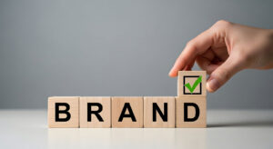 Hand placing checkmark on brand blocks representing accessibility audit and digital experience assurance