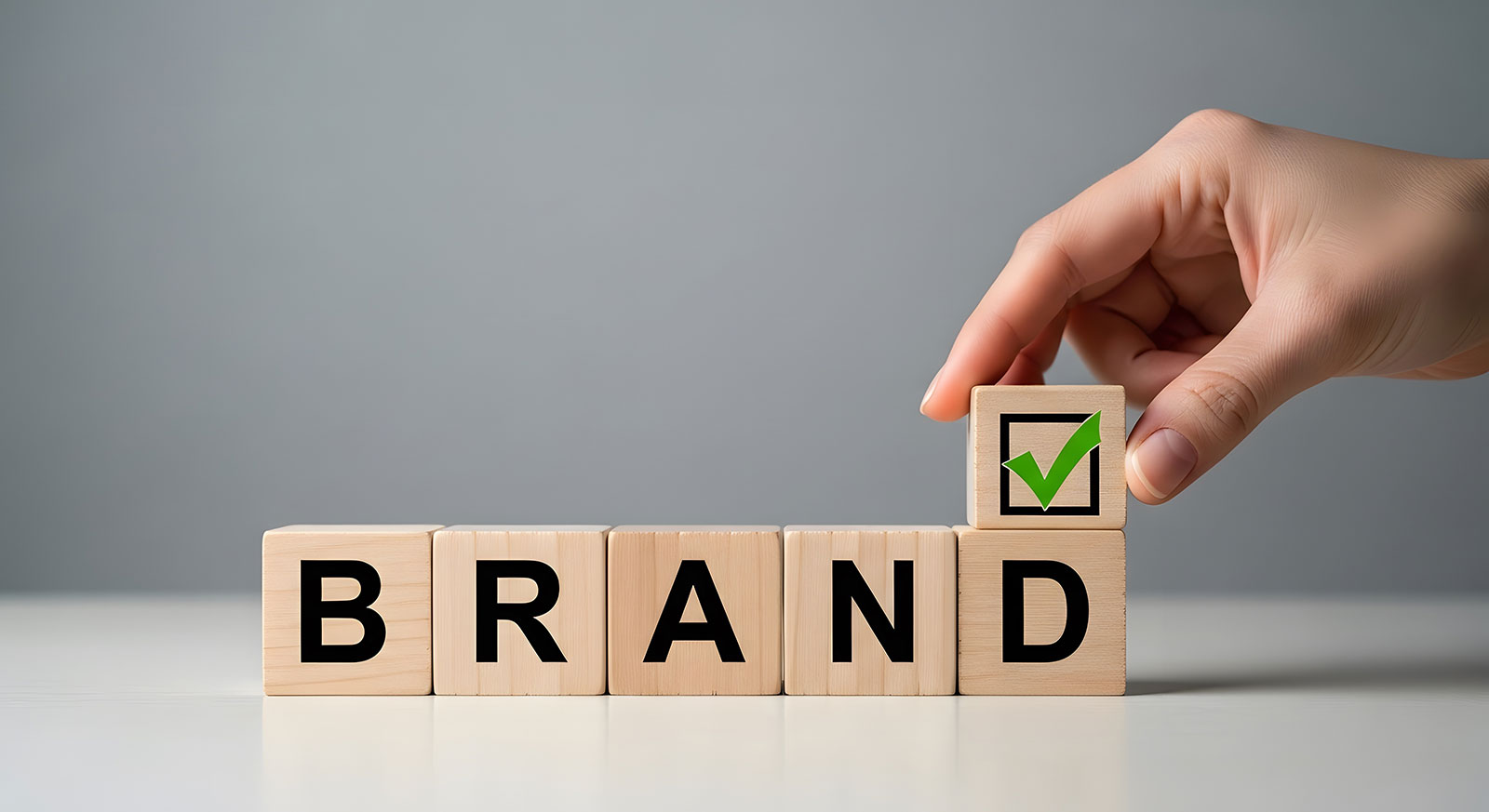 Hand placing checkmark on brand blocks representing accessibility audit and digital experience assurance