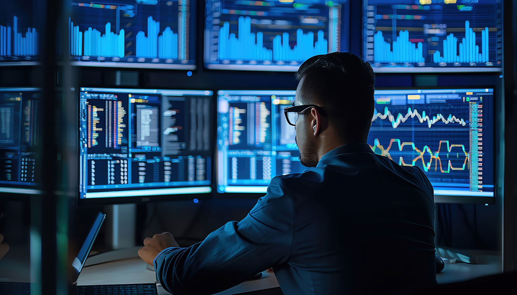 Man monitoring financial charts and data across multiple screens