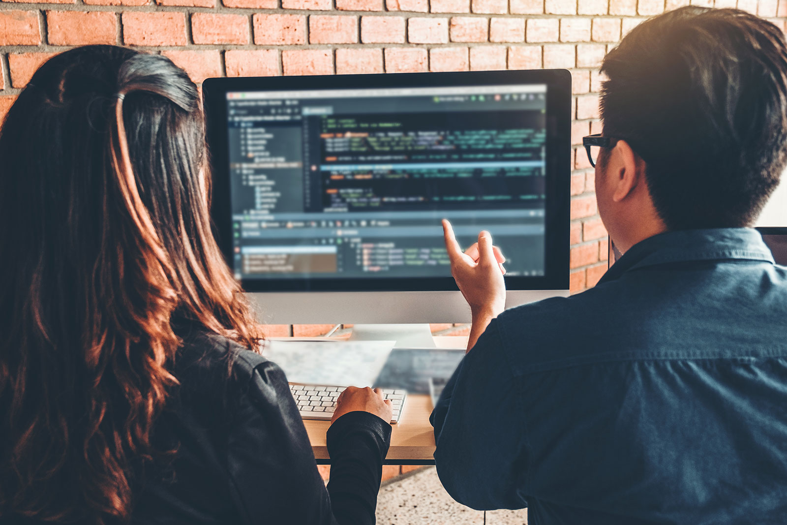 Two developers reviewing code on desktop monitor together