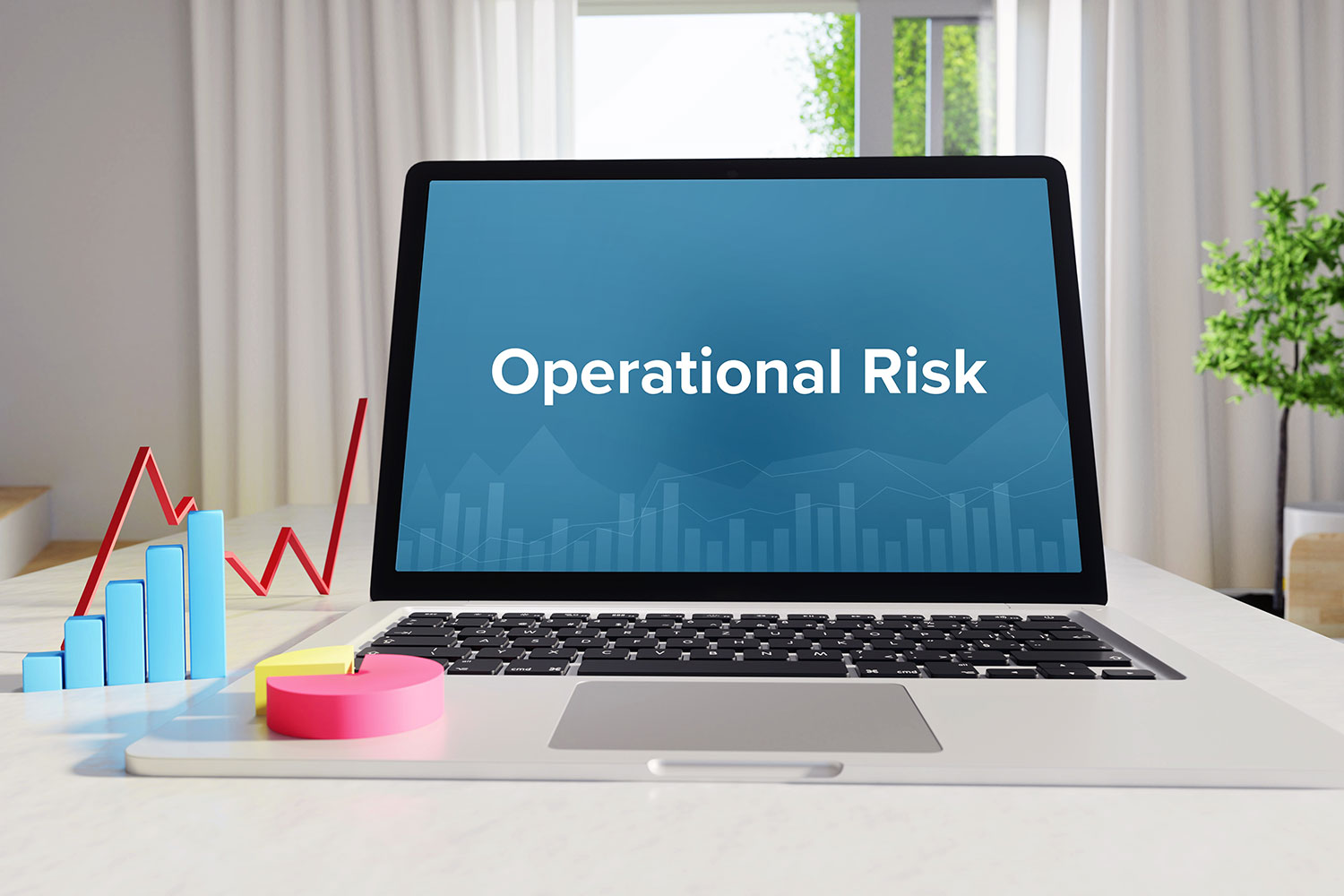 Laptop displaying operational risk text with financial charts and graphs on desk