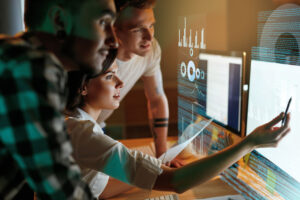 Three professionals analyzing data charts on a glowing screen in a dark room