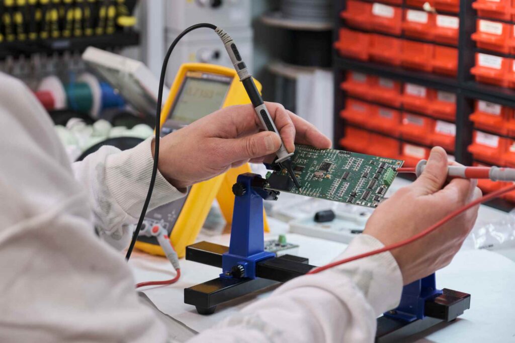 Technician conducting hardware quality assurance testing on electronic circuit board