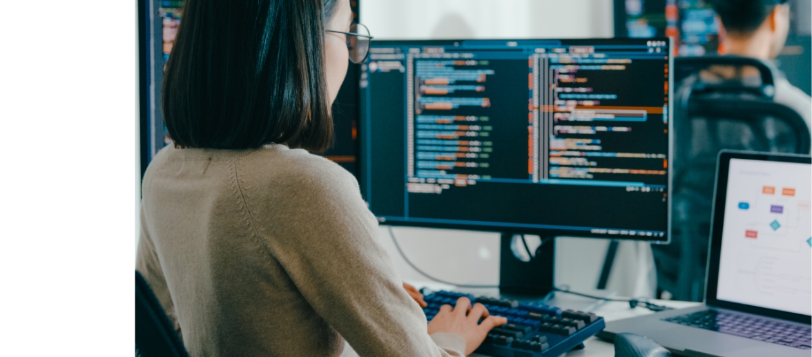 Female developer running performance and security testing on dual monitor workstation
