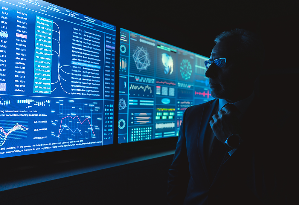 Person analyzing AI data dashboards on large screens in a dark room