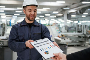 Factory worker reviewing performance charts on a clipboard on the production floor