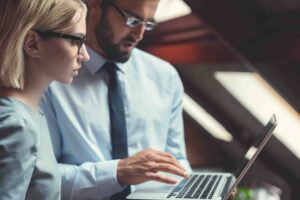 Woman and man looking at cloud operations on laptop