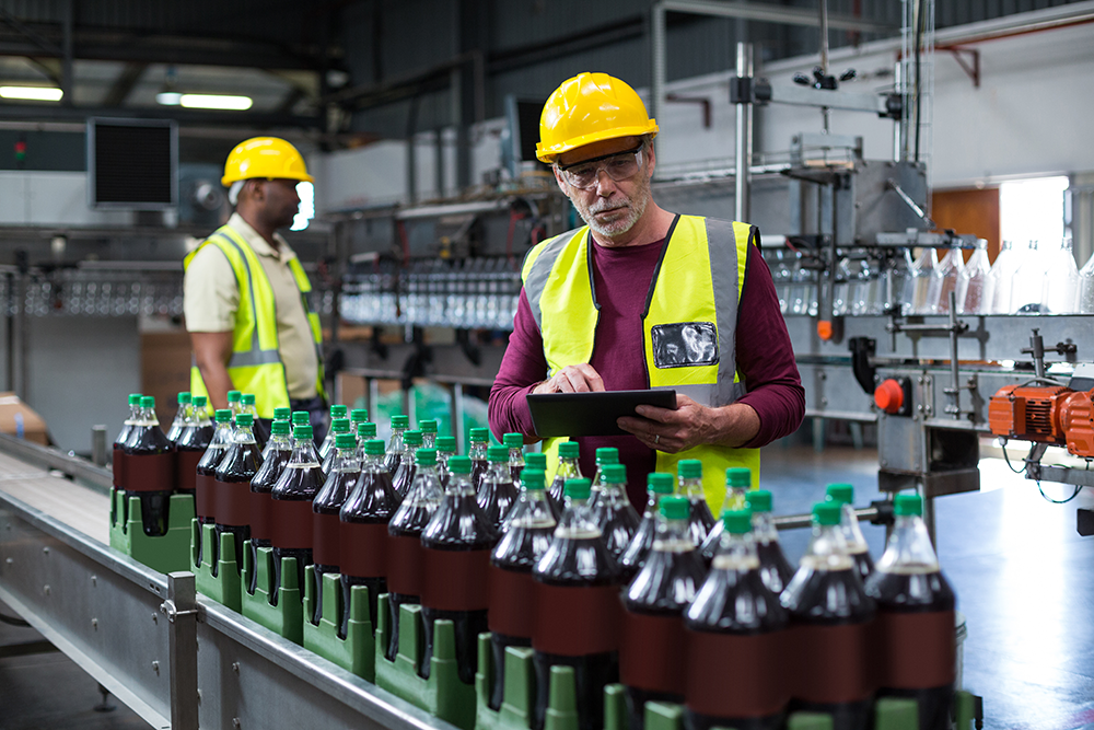 Workers inspecting bottled products on a factory production line