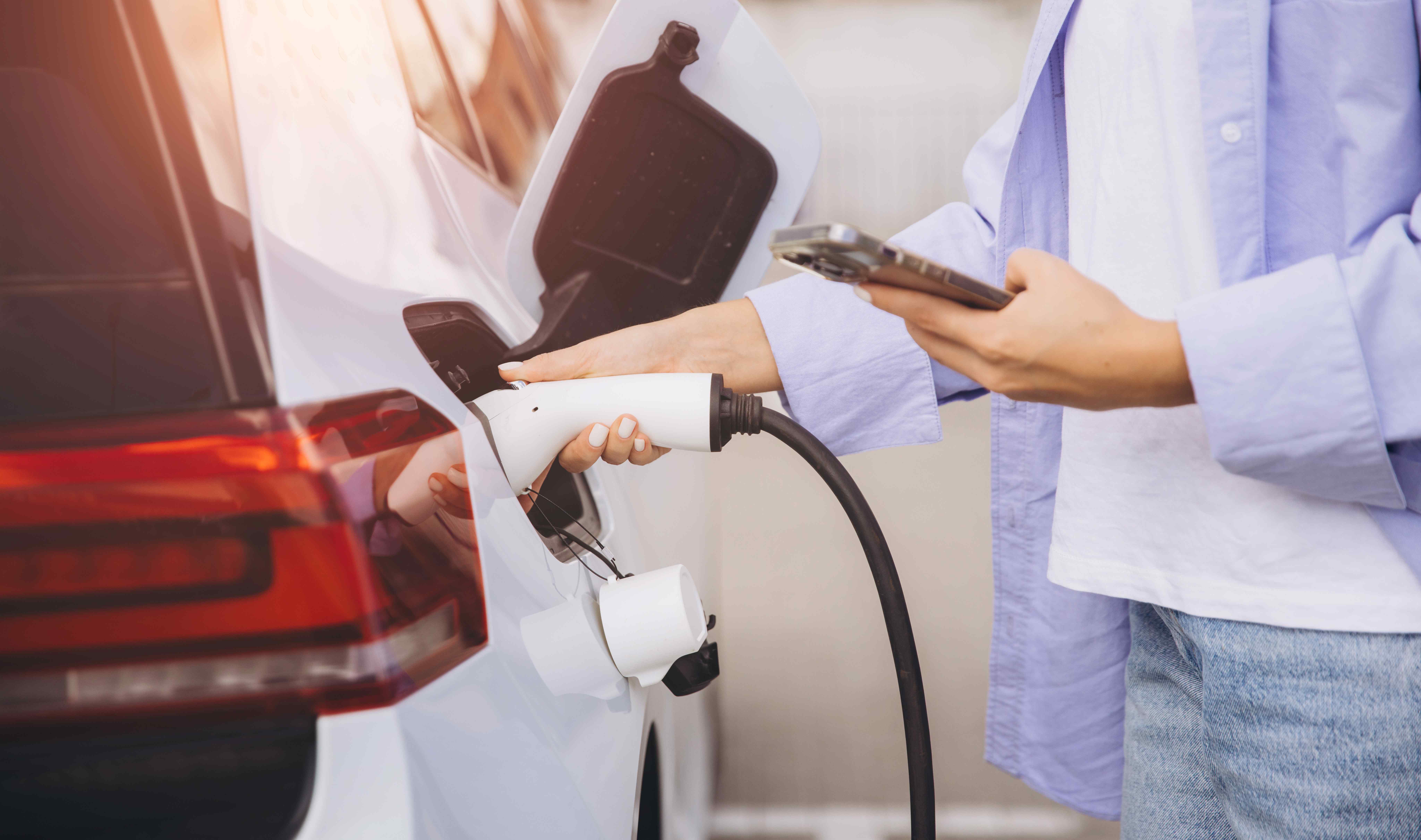 Young woman charging electric car at station while 2026 01 08 02 07 48 utc
