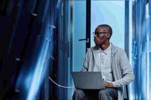 IT professional seated with laptop among server towers
