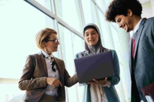 Coworkers smiling while discussing content on laptop screen