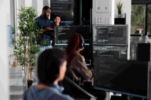 IT staff working together in office with code on displays